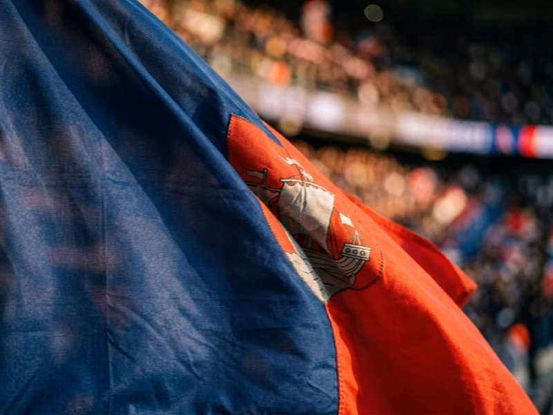 Gros plan drapeau supporter rouge et bleu parisien flottant dans l'ambiance Champions League au Parc des Princes